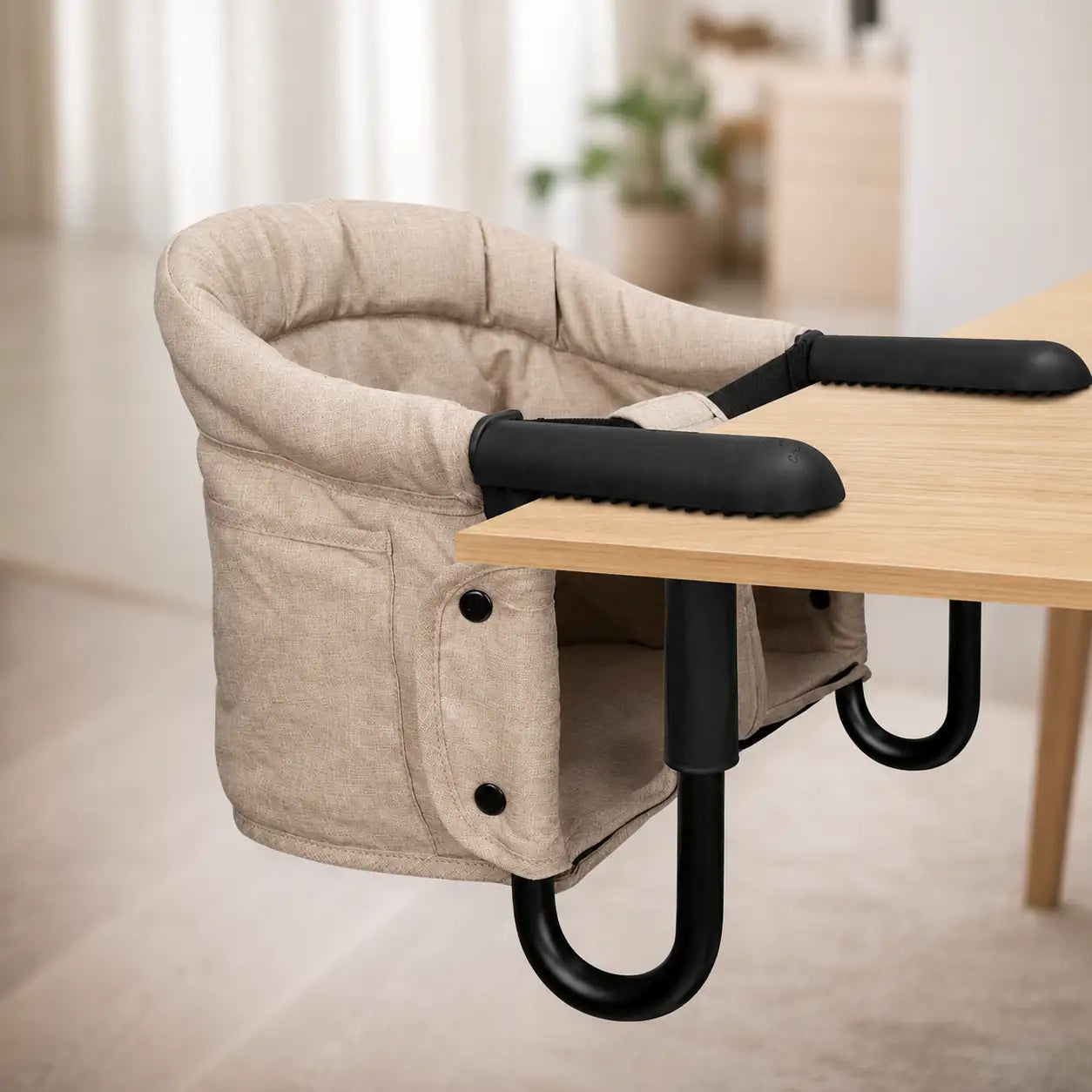 Beige baby hook on high chair attached to a wooden table with a blurred indoor background