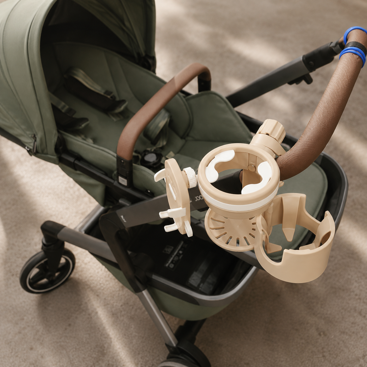 Beige stroller cup holder with phone mount securely attached to a pram handle for convenient drinks and phone storage while out with baby